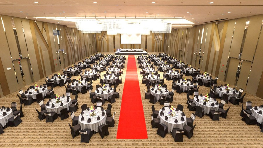 Hotel ballroom with a red carpet aisle between banquet tables