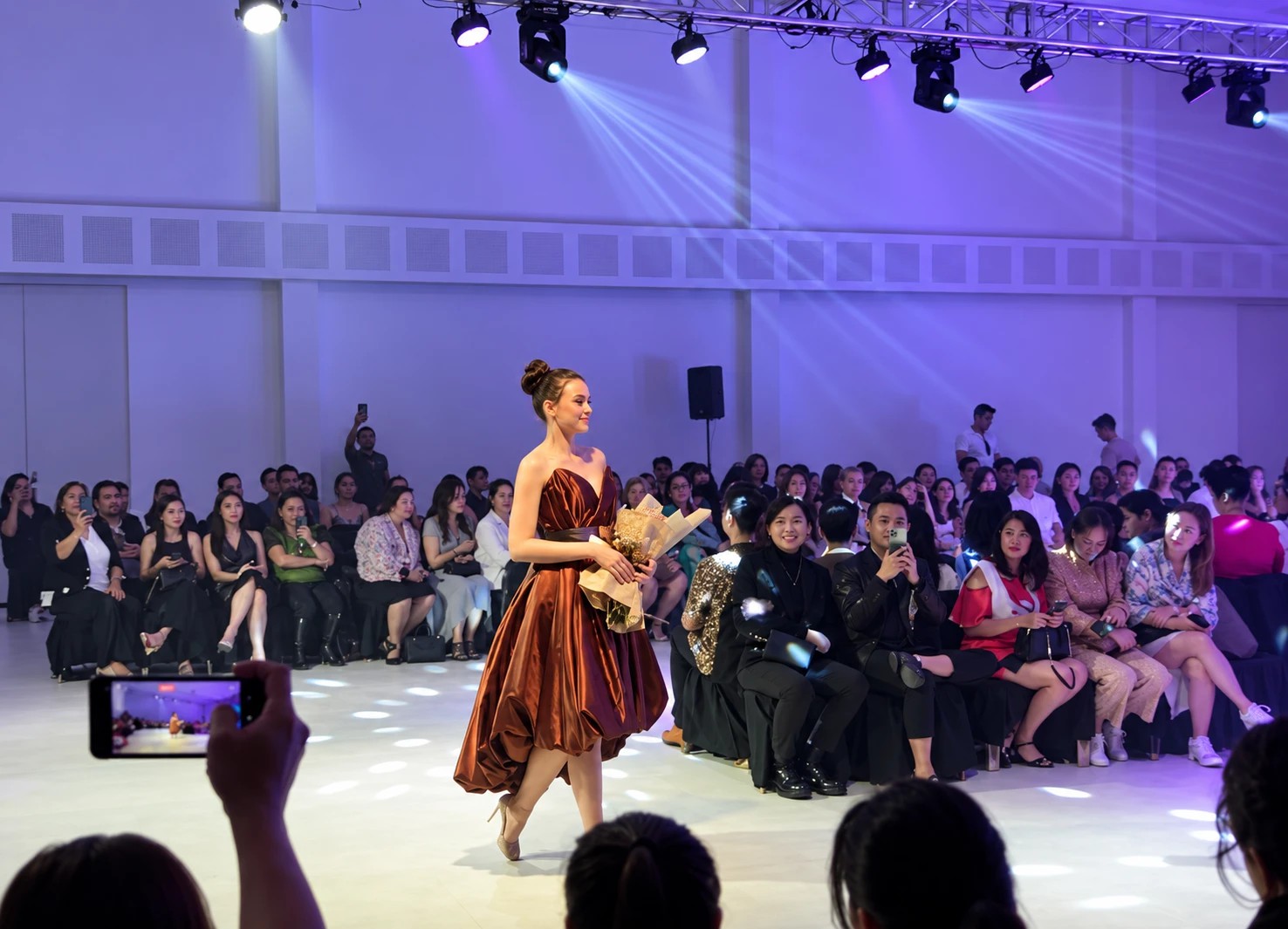 Runway walk under stage lights with the audience seated along the runway